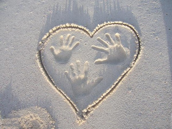 des mains dans un coeur de sable